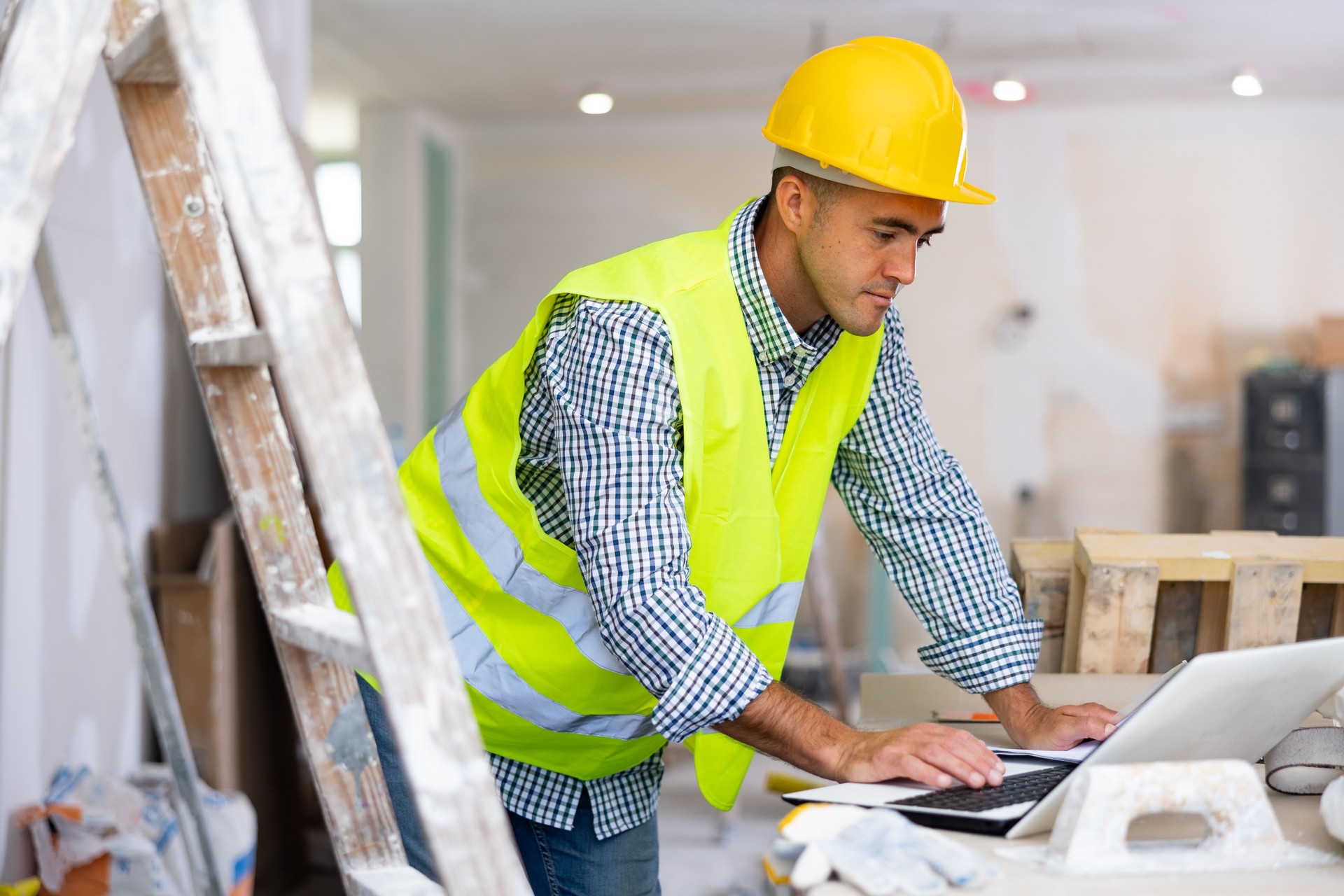 Engenheiro focado verifica o plano de reparo da casa em um laptop