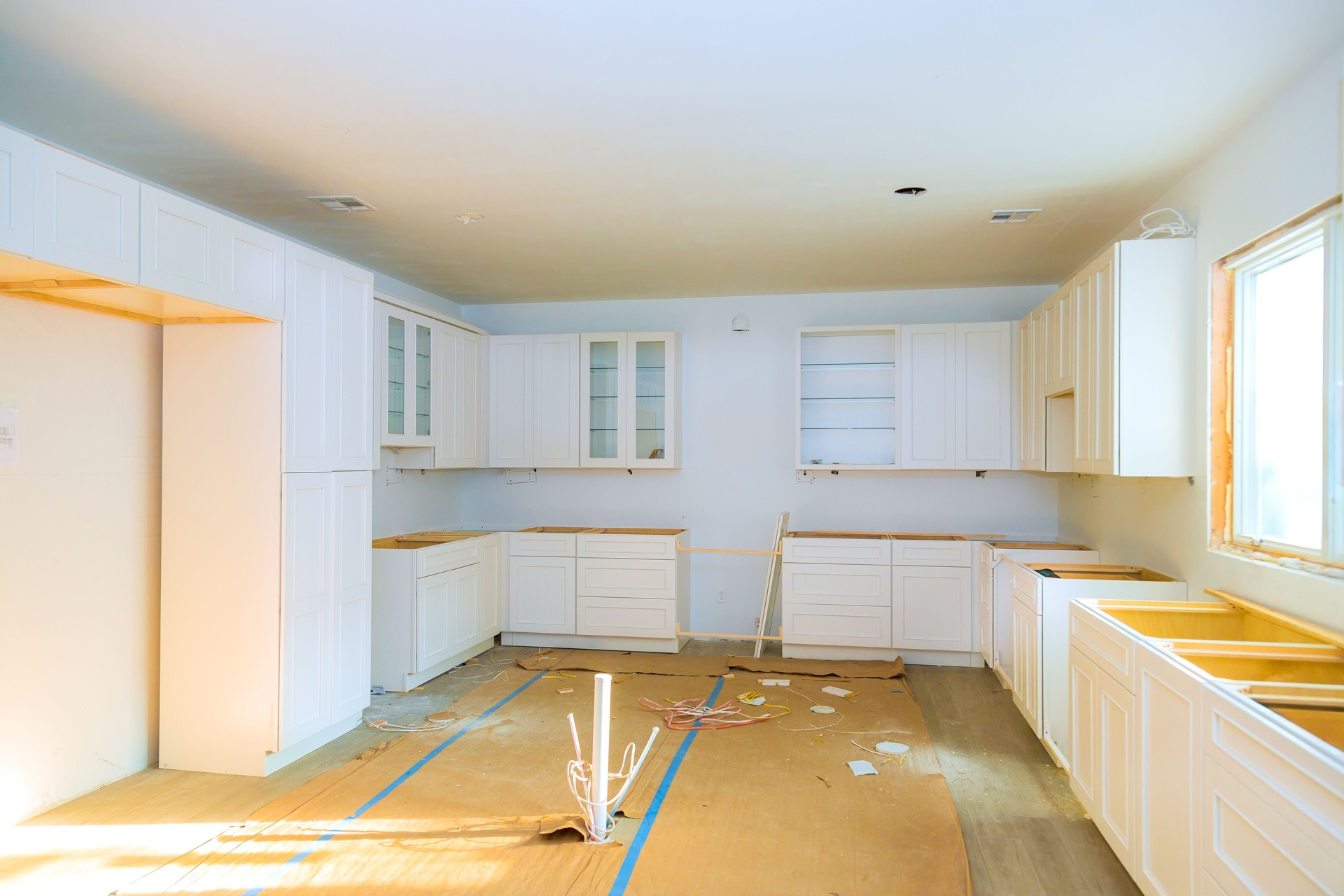 Modern kitchen renovation in progress with empty cabinets and flooring installation taking place